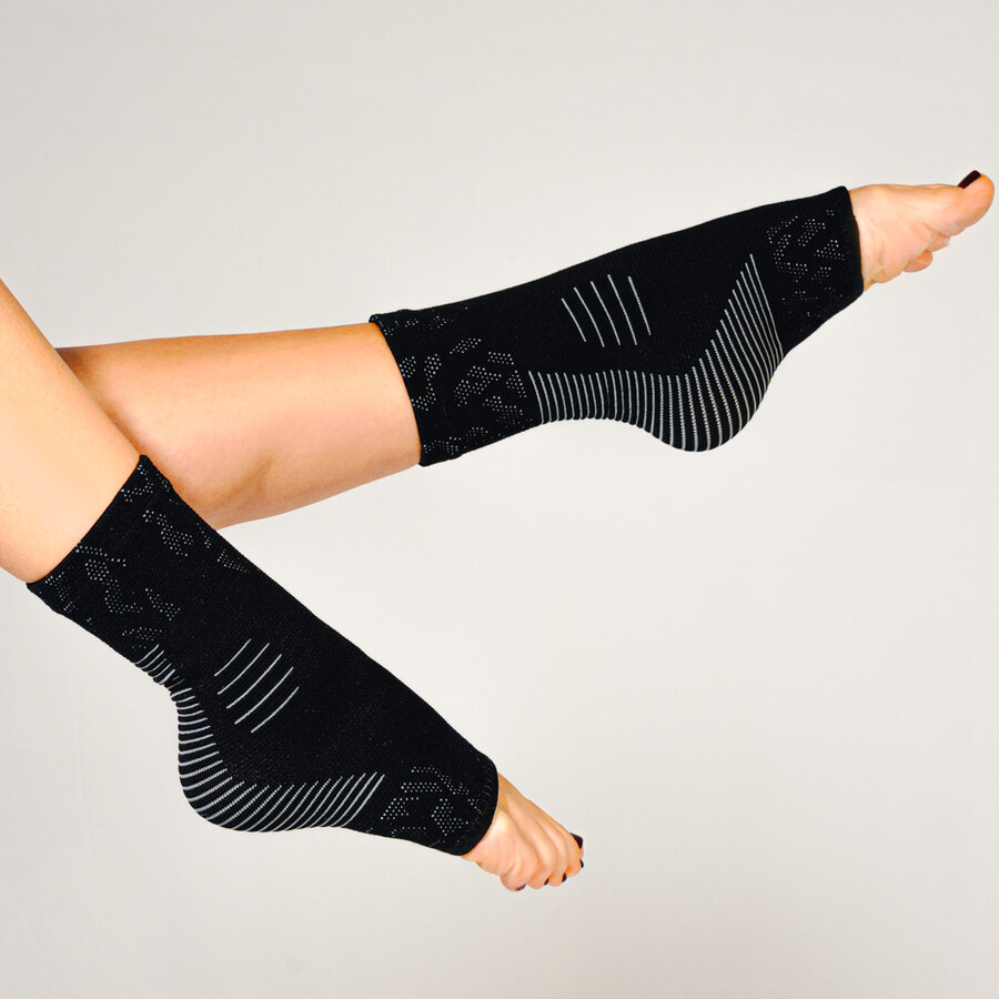 Both legs wearing the black socks against a plain studio background, with the toes left uncovered.