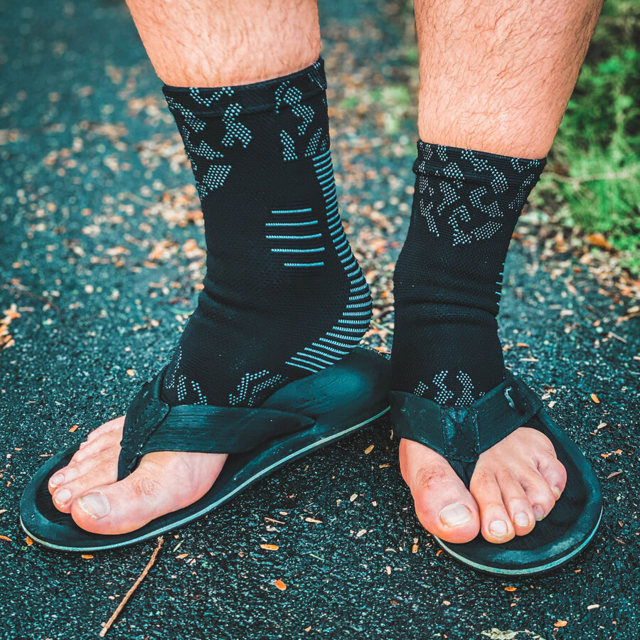 The black socks worn with open sandals on a paved path, the sandal strap running between the bare toes.